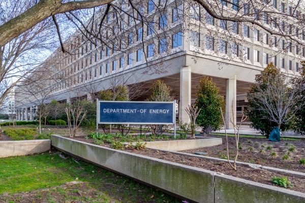 Exterior view of the U.S. Department of Energy headquarters building, surrounded by landscaped greenery and trees.