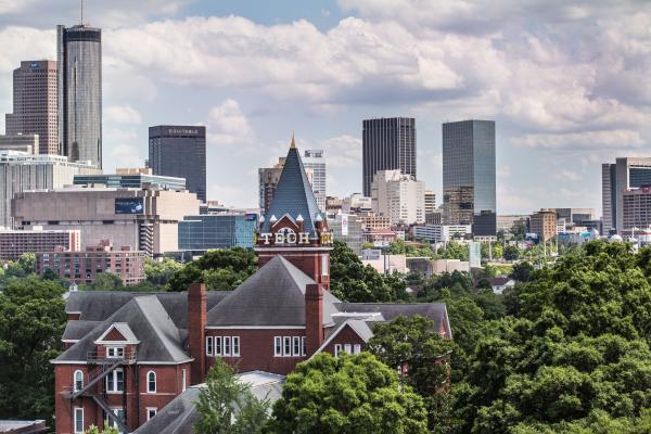 Historic Tech Tower building partially visible among green trees with the Atlanta skyline in the background.