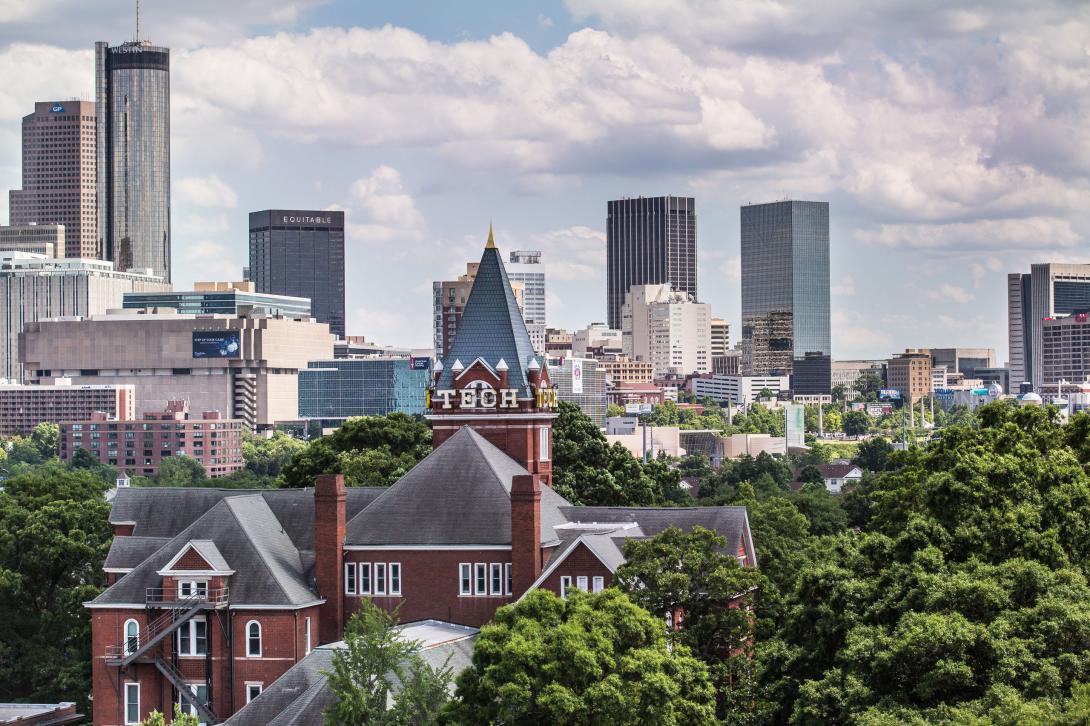 Historic Tech Tower building partially visible among green trees with the Atlanta skyline in the background.